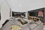 This entertainment room is a music lover's paradise, featuring a collection of guitars displayed on the wall and a full drum set ready for action.