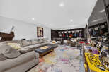 This entertainment room is a music lover's paradise, featuring a large sectional sofa, a foosball table, and a full drum set.
