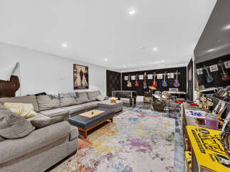 This entertainment room is a music lover's paradise, featuring a large sectional sofa, a foosball table, and a full drum set.