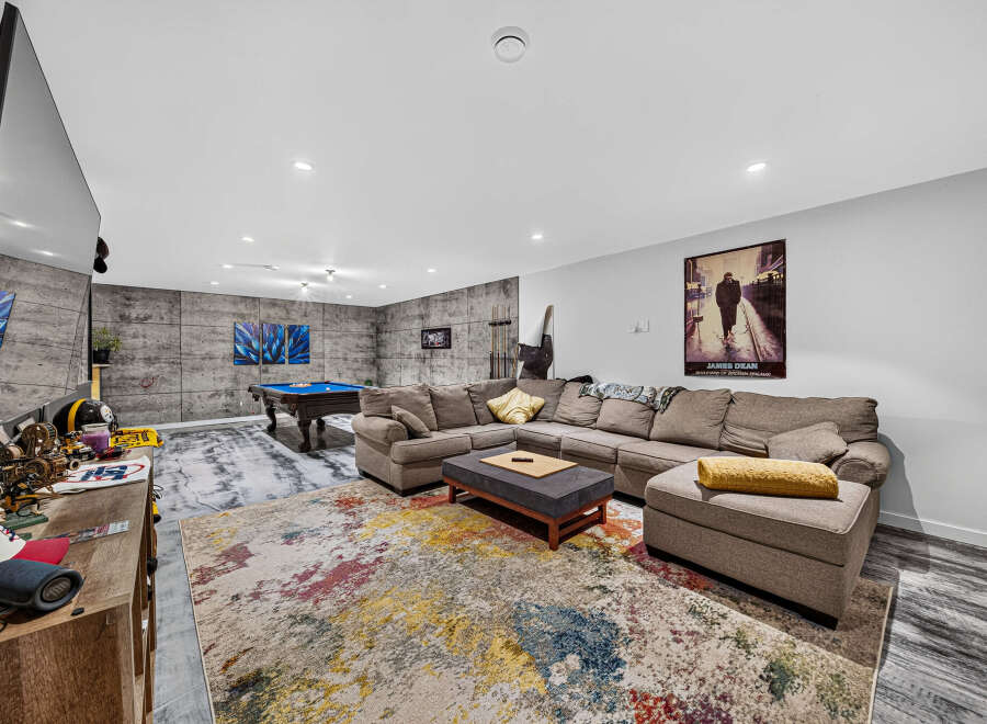 Experience ultimate relaxation in this modern basement living area, featuring a spacious sectional sofa perfect for gatherings.