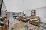Experience ultimate relaxation in this modern basement living area, featuring a spacious sectional sofa perfect for gatherings.