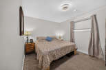 This cozy bedroom features a comfortable queen-size bed adorned with a patterned comforter and a blue accent pillow.