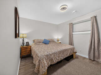 This cozy bedroom features a comfortable queen-size bed adorned with a patterned comforter and a blue accent pillow.