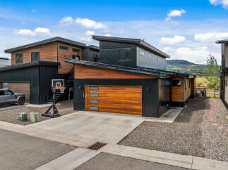 Experience modern living in this stunning home featuring a sleek, dark exterior contrasted with warm wood accents.
