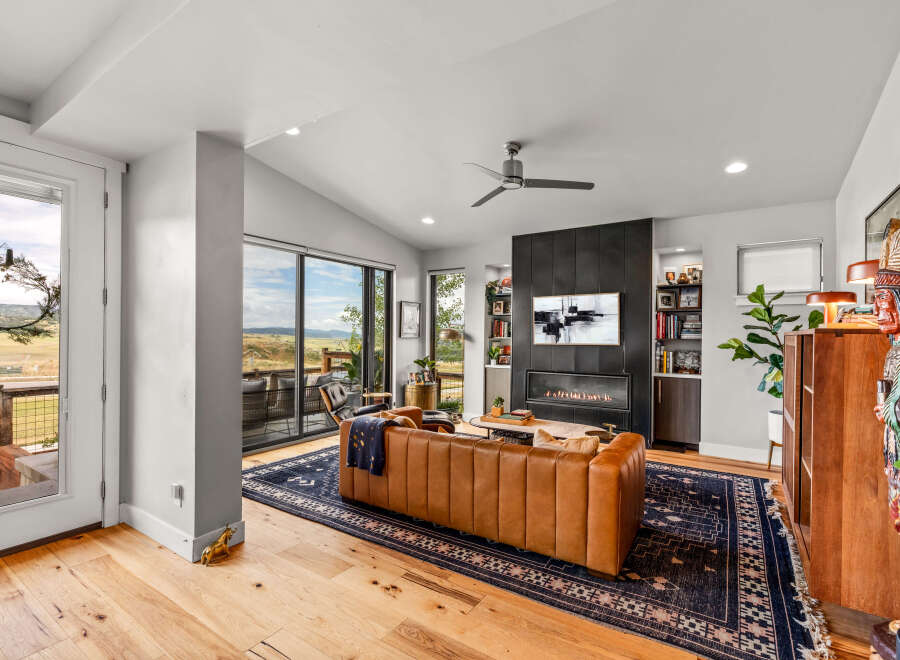 Experience modern living in this stunning living room featuring a sleek fireplace and expansive windows with breathtaking views.
