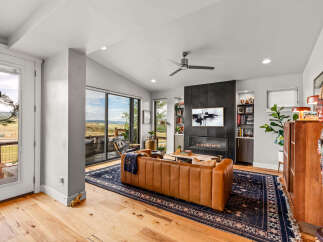 Experience modern living in this stunning living room featuring a sleek fireplace and expansive windows with breathtaking views.