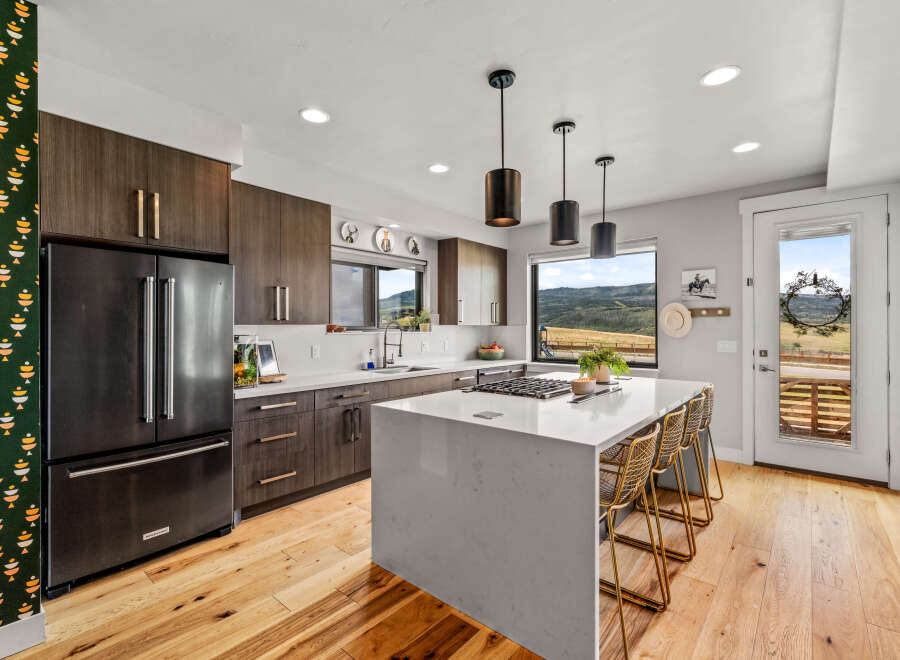 Experience modern living in this stunning kitchen featuring dark wood cabinetry and a sleek white quartz island.