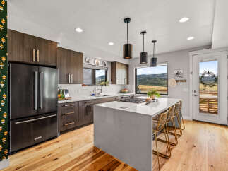 Experience modern living in this stunning kitchen featuring dark wood cabinetry and a sleek white quartz island.