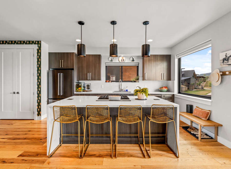Experience modern living in this stunning kitchen featuring dark wood cabinetry, a sleek white island with bar seating, and contemporary pendant lighting.