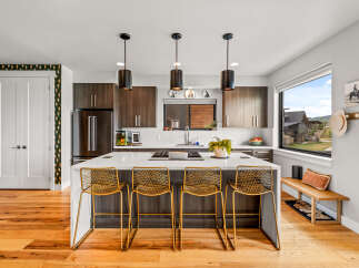 Experience modern living in this stunning kitchen featuring dark wood cabinetry, a sleek white island with bar seating, and contemporary pendant lighting.