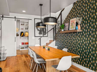 This dining area boasts a modern aesthetic with a large wooden table and white chairs, perfect for family gatherings.