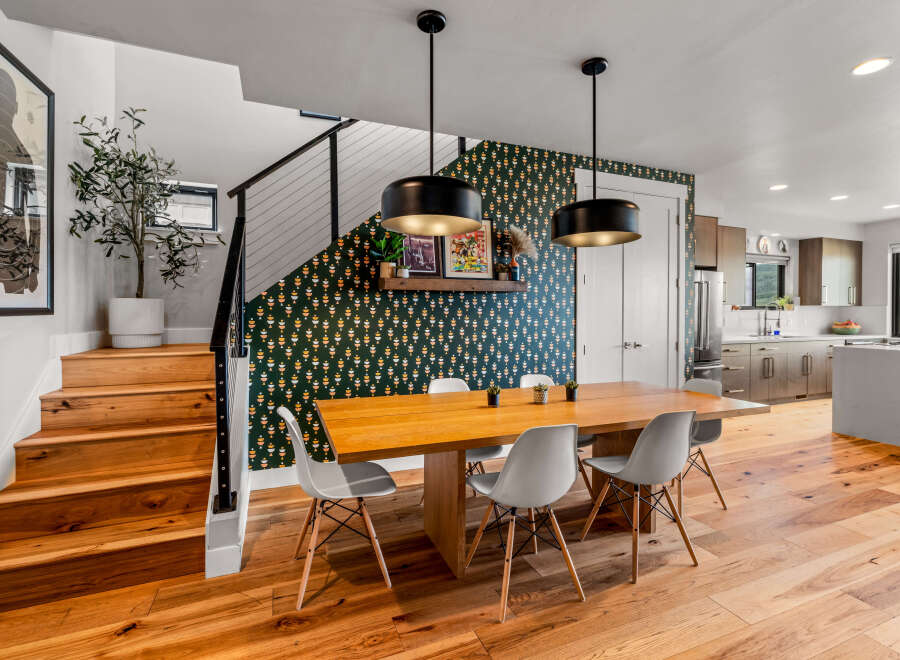 Experience modern living in this stunning home featuring a chic dining area with a statement wallpaper and pendant lights.