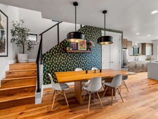 Experience modern living in this stunning home featuring a chic dining area with a statement wallpaper and pendant lights.