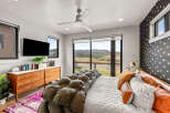 Experience modern luxury in this stunning bedroom featuring a sleek ceiling fan and a large flat-screen TV.