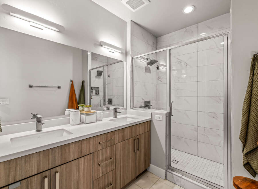 Experience modern luxury in this stunning bathroom featuring a spacious double vanity with sleek cabinetry and a bright, airy walk-in shower.