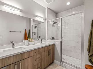 Experience modern luxury in this stunning bathroom featuring a spacious double vanity with sleek cabinetry and a bright, airy walk-in shower.