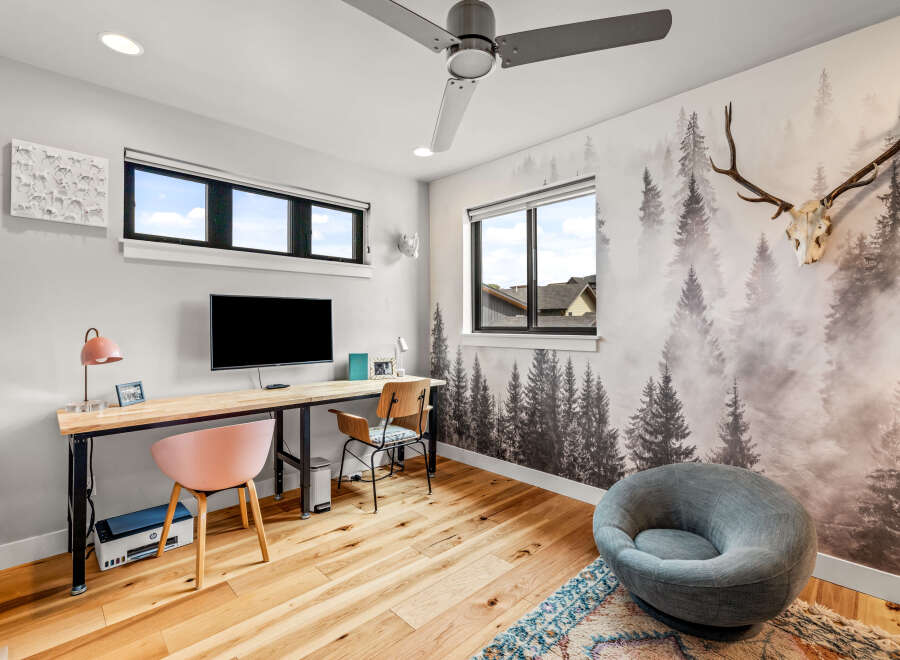 This modern home office features a large wooden desk with a mounted TV, perfect for productivity and entertainment.