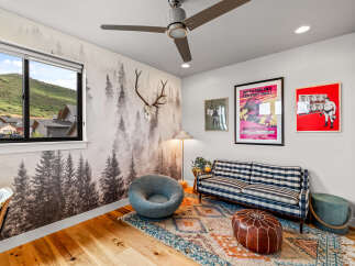 Experience a unique living space with a captivating forest-themed wallpaper and a stunning mountain view from the large window.