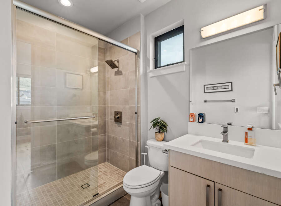 Experience modern comfort in this beautifully appointed bathroom, featuring a sleek glass-enclosed shower with tiled walls and a convenient handheld showerhead.