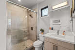 Experience modern comfort in this beautifully appointed bathroom, featuring a sleek glass-enclosed shower with tiled walls and a convenient handheld showerhead.