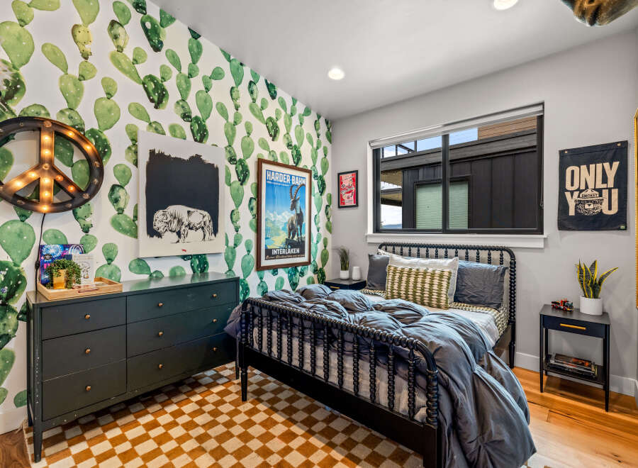 This vibrant bedroom features a playful cactus-themed wallpaper that adds a unique personality to the space.