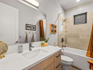 This modern bathroom features a sleek vanity with a vessel sink and a contemporary faucet, complemented by a large vanity mirror.