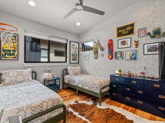 This playful children's bedroom features two twin beds with charming patterned quilts, perfect for siblings or sleepovers.
