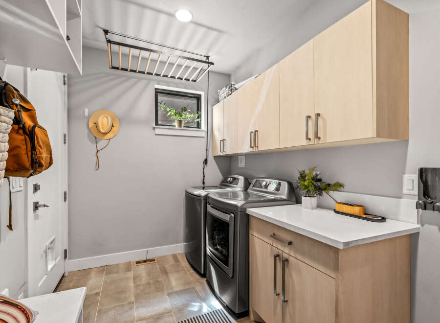 This laundry room offers ample storage with overhead cabinets and a convenient countertop space.