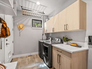 This laundry room offers ample storage with overhead cabinets and a convenient countertop space.