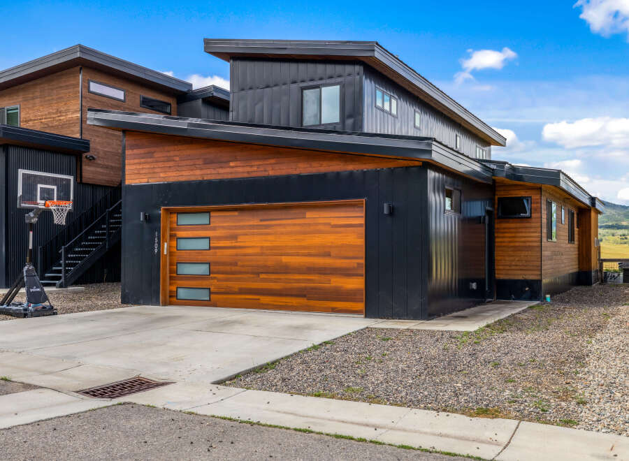 Experience modern living in this stunning home featuring a sleek black metal exterior complemented by warm wood accents.