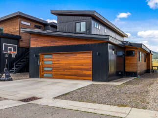 Experience modern living in this stunning home featuring a sleek black metal exterior complemented by warm wood accents.