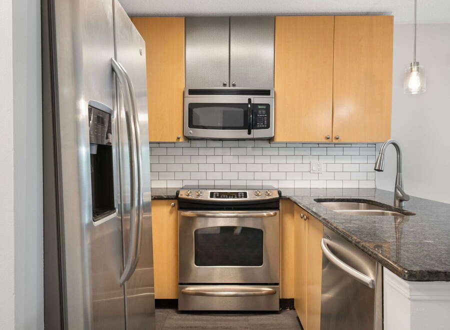 Discover this modern kitchen featuring sleek stainless steel appliances, including a refrigerator, microwave, and oven.