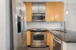 Discover this modern kitchen featuring sleek stainless steel appliances, including a refrigerator, microwave, and oven.
