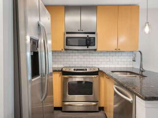 Discover this modern kitchen featuring sleek stainless steel appliances, including a refrigerator, microwave, and oven.