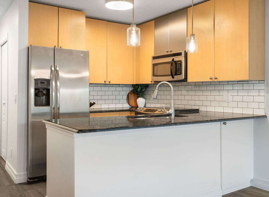 This modern kitchen boasts sleek stainless steel appliances, including a side-by-side refrigerator and a built-in microwave.