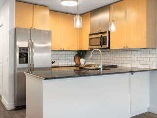 This modern kitchen boasts sleek stainless steel appliances, including a side-by-side refrigerator and a built-in microwave.
