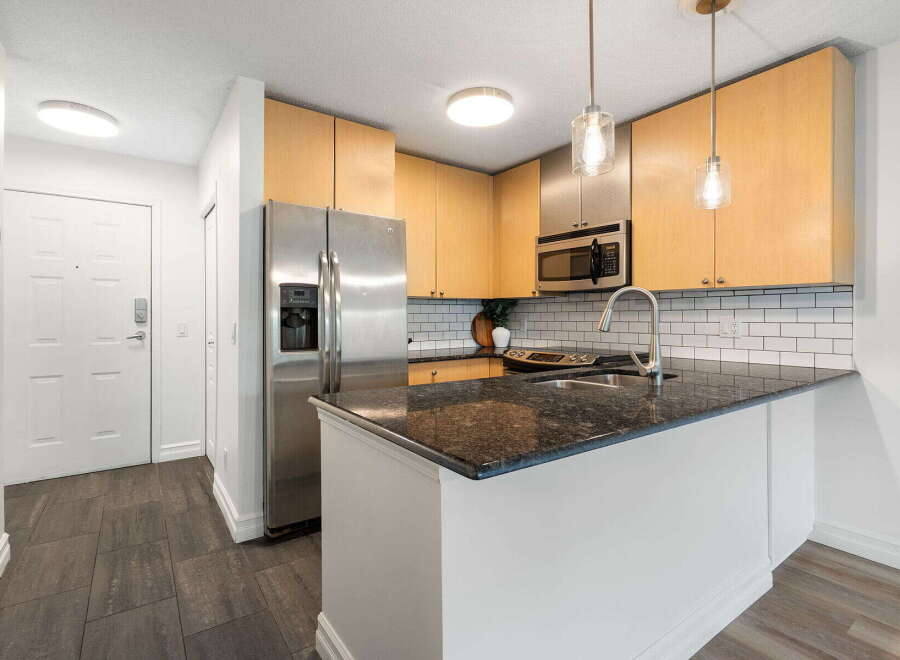 Discover this charming kitchen featuring sleek stainless steel appliances, including a side-by-side refrigerator and a built-in microwave.
