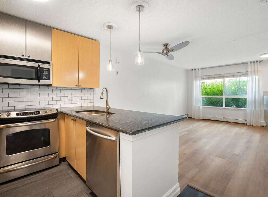 Discover this modern kitchen featuring stainless steel appliances, including a microwave and oven, complemented by sleek cabinetry and a granite countertop.
