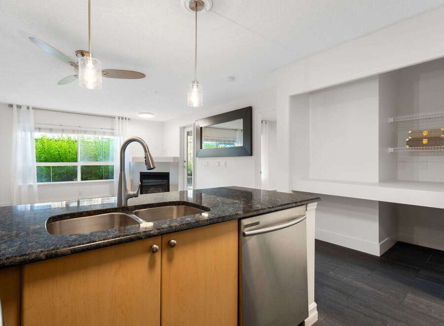This modern kitchen features a spacious island with a double sink and granite countertops, perfect for meal preparation and entertaining.