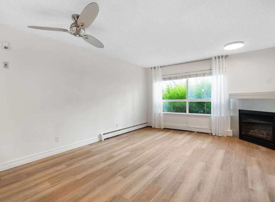 Experience modern living in this spacious room featuring a sleek ceiling fan and a cozy gas fireplace.