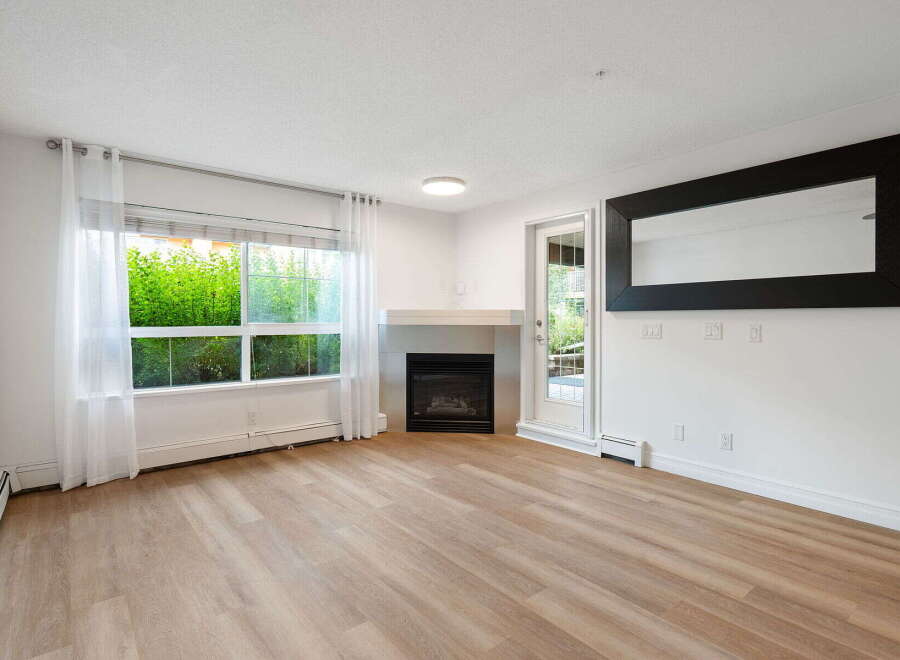 Experience modern living in this bright and airy living room, featuring a cozy fireplace and large windows that flood the space with natural light.