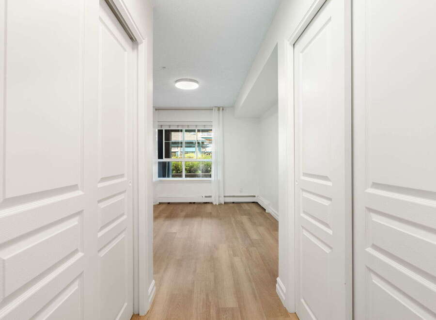 Step into this bright and airy hallway, featuring pristine white doors that lead to spacious rooms.