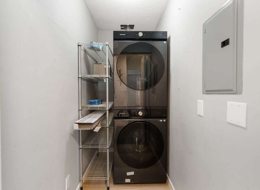 This laundry room features a sleek, black Samsung stacked washer and dryer unit, perfect for maximizing space.