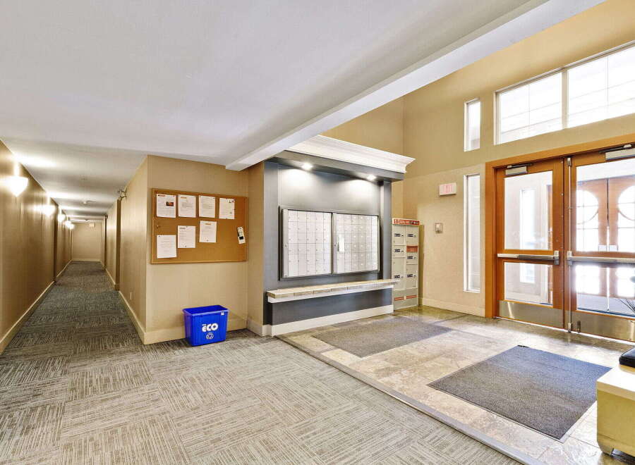 Welcome to this inviting building lobby, featuring a long, well-lit hallway and a convenient mail area with secure mailboxes.