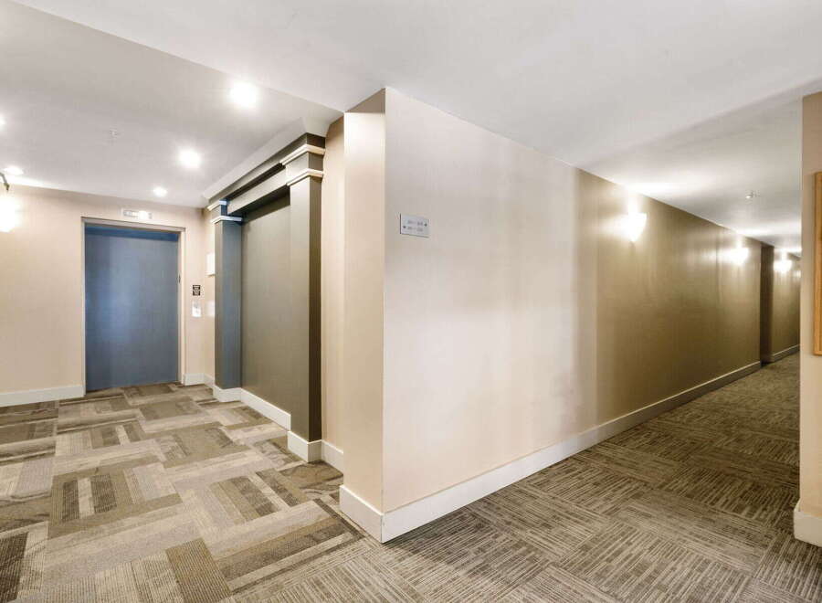 Step into this inviting hallway featuring a modern elevator and a stylish, geometric carpet pattern.