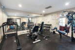 This well-equipped home gym features a variety of cardio machines, including a treadmill and recumbent bike, perfect for your daily workouts.