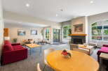 This inviting common area features a cozy fireplace, comfortable seating arrangements, and large windows that flood the space with natural light.