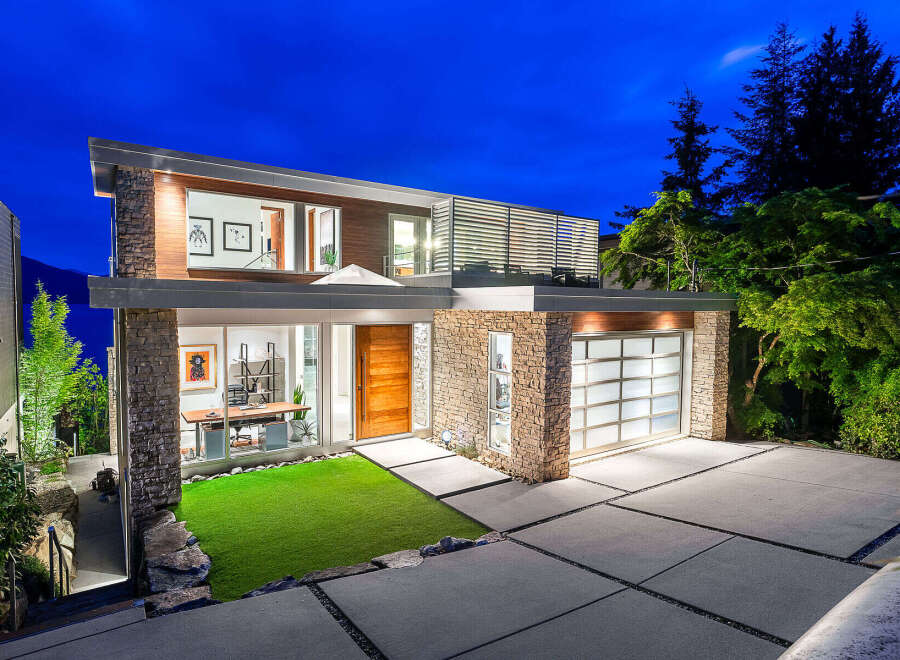 Experience modern luxury in this stunning architectural home, featuring a striking stone and wood facade.