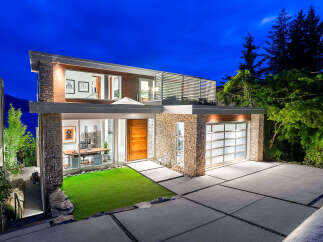 Experience modern luxury in this stunning architectural home, featuring a striking stone and wood facade.