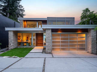Experience modern luxury in this stunning home featuring a sleek design with stone accents and a frosted glass garage door.